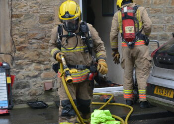 Fire officers wearing breathing apparatus exit the home on Baliol Street