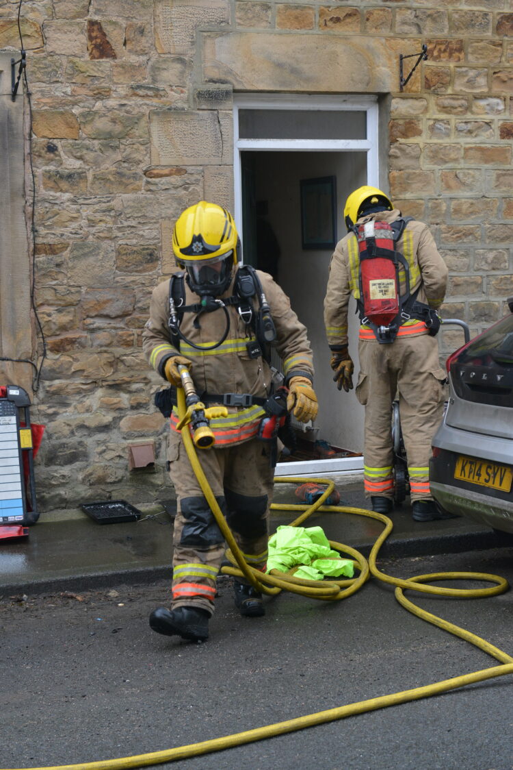 Fire officers wearing breathing apparatus exit the home on Baliol Street